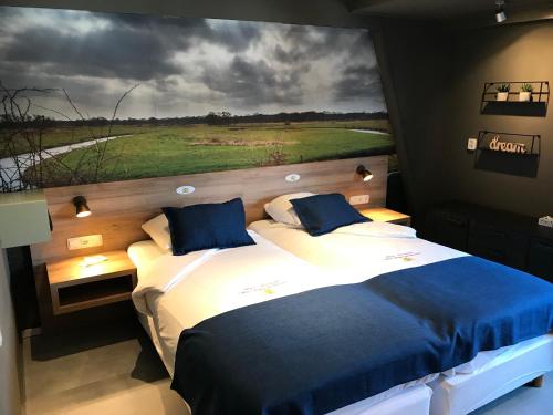 two beds in a room with a large painting on the wall at Hotel Het Wapen van Drenthe in Roden