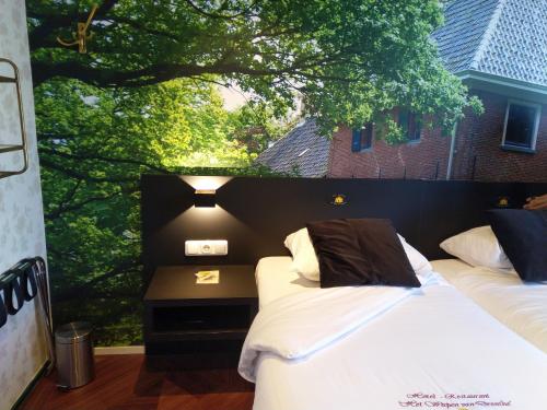 two beds in a room with a large window at Hotel Het Wapen van Drenthe in Roden