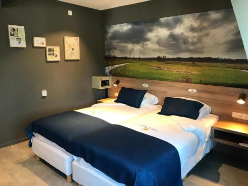 a bedroom with two beds with a painting on the wall at Hotel Het Wapen van Drenthe in Roden
