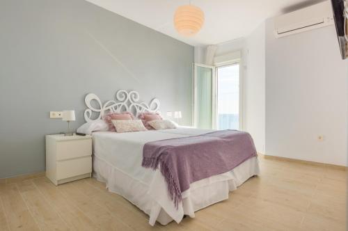 a white bedroom with a large bed with pink pillows at Seafront La Malagueta I in Málaga