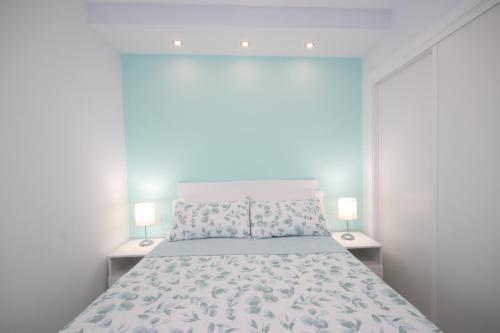 a white bedroom with a large bed with two lamps at Apartment with terrace in Playa de Las Americas in Playa de las Americas