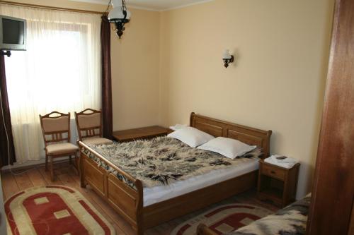 a bedroom with a bed and two chairs and a window at Cabana Iza in Bîrsana