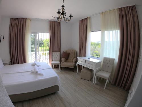a hotel room with a bed and a desk and windows at Alaçatı La Vista in Alaçatı