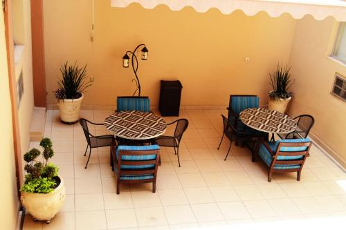 2 Tische und Stühle in einem Zimmer mit Pflanzen in der Unterkunft Hotel America Centro in Los Mochis