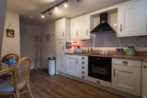uma cozinha com armários brancos, uma mesa e um fogão em The Old Surgery em Thirsk