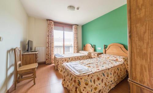 a hotel room with two beds and a television at LA POSADA DE HIGUERUELA in Higueruela