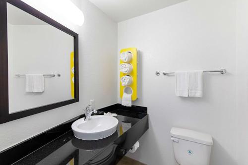 a bathroom with a sink and a mirror and a toilet at Motel 6 Austin Airport in Austin