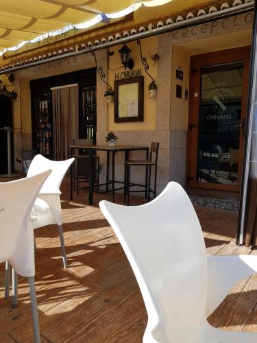 a patio with white chairs and a table at Hotel Carvajal in Torrejón el Rubio