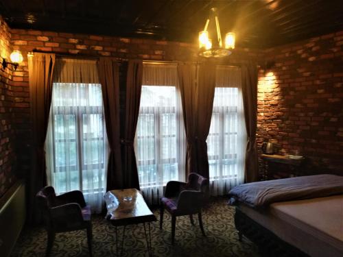 a bedroom with a bed and two chairs and windows at Kayıbeyi Hotel & Restaurant in Bursa