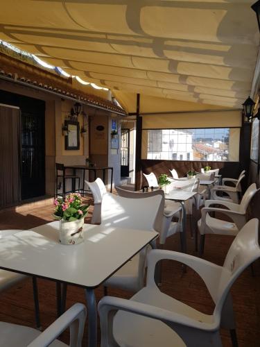 a row of tables and white chairs on a patio at Hotel Carvajal in Torrejón el Rubio
