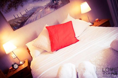 a bedroom with a bed with a red pillow on it at The Rising Sun Inn in Waterlooville