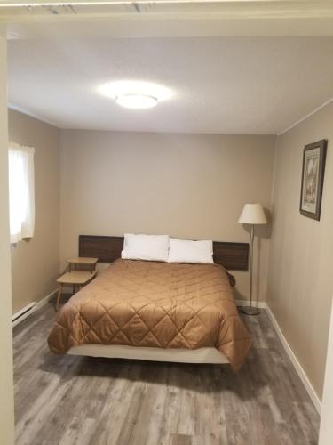 a bedroom with a bed and a table and a lamp at Apple Tree Inn in Penticton