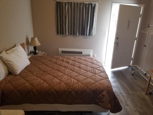 a bedroom with a bed and a door with a window at Apple Tree Inn in Penticton