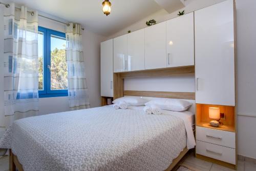 1 dormitorio con 1 cama con armarios blancos y ventana en KUĆA ZA ODMOR- LOVRO en Mali Lošinj