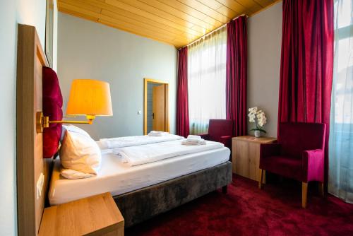 une chambre d'hôtel avec un lit et une chaise dans l'établissement Hotel Fränkischer Hof, à Kitzingen