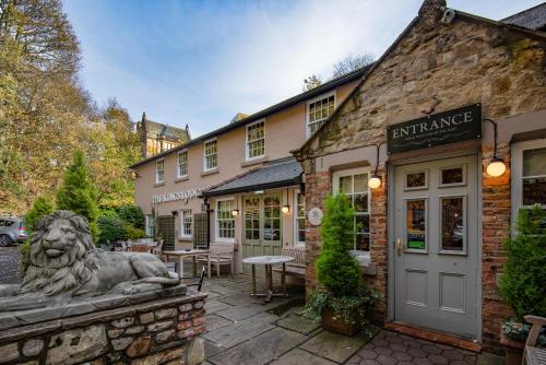 a stone building with a lion statue in front of it at The Kingslodge Inn - The Inn Collection Group in Durham