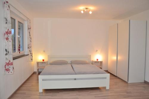 um quarto com uma cama branca e 2 candeeiros em Ferienwohnung Bühlingen em Rottweil