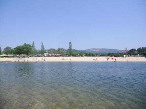 a beach with people sitting on the sand and water at Casas de Campo Podence in Macedo de Cavaleiros