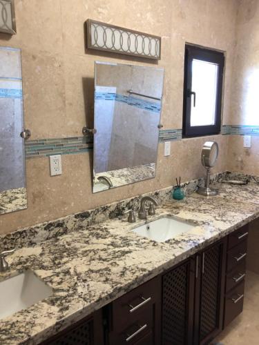 a bathroom with two sinks and two mirrors at The Meridian at Lighthouse Point in West Bay
