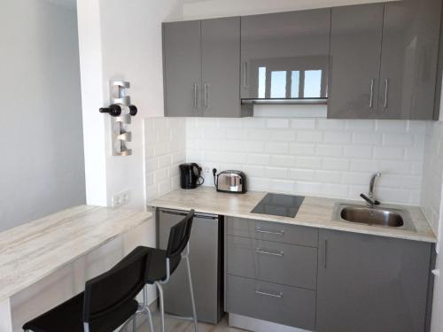 a kitchen with a sink and a counter with chairs at Ático Los Lomos in El Paso