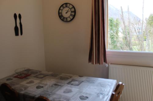 Una habitación con una mesa y un reloj en la pared. en Appartement Nolhan, en Cauterets