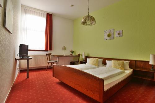 a bedroom with a bed and a desk and a television at Landgasthof & Hotel KRONE Eischleben in Ichtershausen