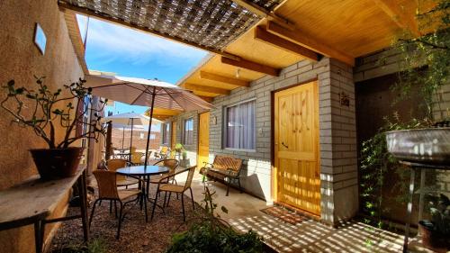 un patio con mesa, sillas y sombrilla en Hostal Ckamai, en San Pedro de Atacama