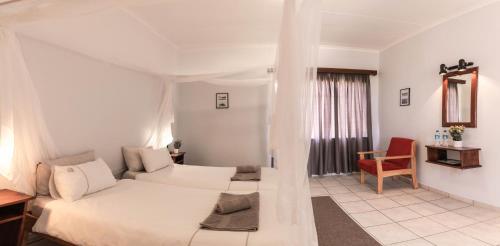 Maltahöhe Hotel في مالتهوه: غرفة نوم بيضاء بسرير وكرسي احمر