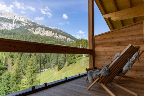 a rocking chair on a porch with a view of a mountain at Dolomiti Lodge Alverà in Cortina dʼAmpezzo