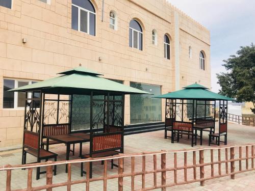 a group of benches and umbrellas in front of a building at Jabal Al Akhdar Grand Hotel in Jabal Al Akhdar