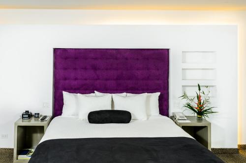 a bedroom with a large bed with a purple headboard at Riande Aeropuerto Hotel Casino in Tocumen