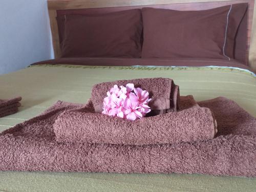 einen Haufen Handtücher auf einem Bett mit einer rosa Blume in der Unterkunft Casa da Fajã - RRAL nº 635 in Fajã da Caldeira de Santo Cristo