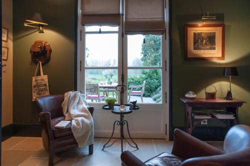 a living room with a couch and a chair and a window at Les Buis de Boscherville Gite in Hénouville