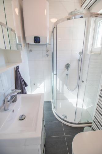 a white bathroom with a shower and a sink at Mary in Omiš