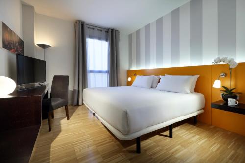 a bedroom with a bed and a desk and a television at Exe Tres Cantos in Tres Cantos