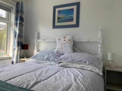 a white bedroom with a bed and a window at Lagoon View Cottage in Millisle