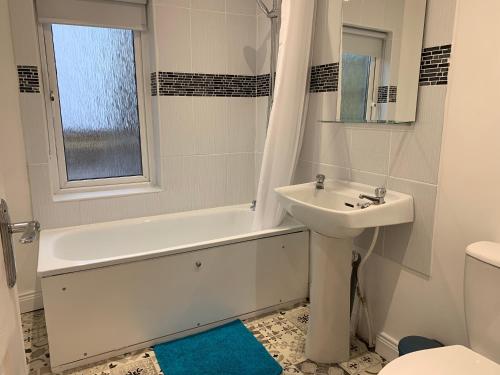 a bathroom with a sink and a tub and a toilet at Lagoon View Cottage in Millisle