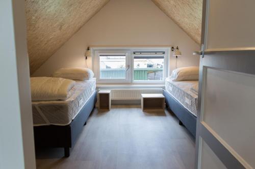 two beds in a small room with a window at Vakantiehuis de Pondok in Gaastmeer