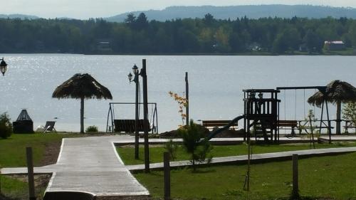 a park with a playground next to a lake at Les Chalets Baie Cascouia in Lac Kénogami