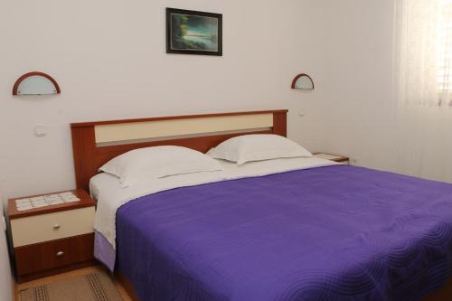 sypialnia z łóżkiem z fioletowym kocem w obiekcie Apartmani Mary 2 plus 1 w mieście Kukljica