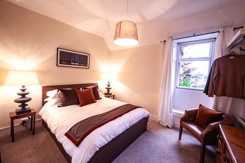 um quarto com uma cama, uma janela e uma cadeira em Butler's Apartment. Flat 5, Dalmore House, Helensburgh, Scotland G84 8JP em Helensburgh