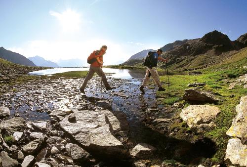 two people walking across a stream in the mountains at Dorf Alm in Obergurgl