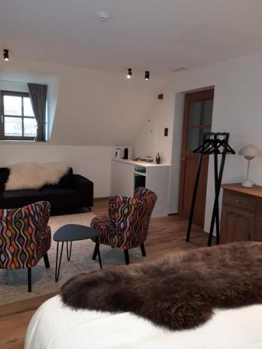 a living room with a bed and chairs and a couch at B&B 't Hof van Spiere in Spiere