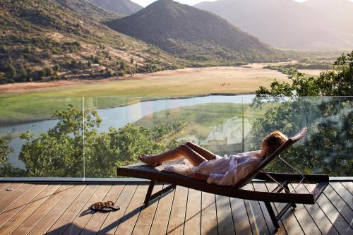a woman laying in a hammock on a deck overlooking a lake at Vik Chile in San Vicente de Taguatagua