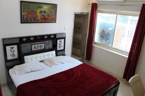 a bedroom with a bed with a red blanket and a window at Best B&B in Orchha in Orchha