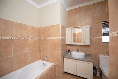 a bathroom with a bath tub and a sink at Nkomazi Kruger Lodge & Spa in Malelane