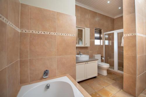 a bathroom with a tub and a toilet and a sink at Nkomazi Kruger Lodge & Spa in Malelane