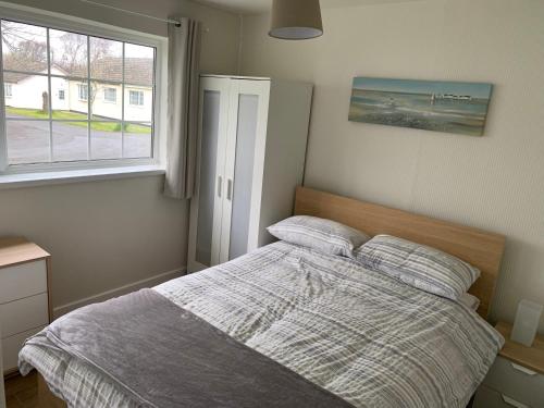 a bedroom with a bed with two pillows and a window at 24 Gower Holiday Village in Reynoldston