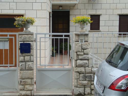 a white car parked in front of a building with a gate at Apartments K & K Dubrovnik in Dubrovnik