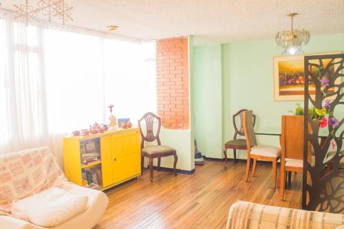 a living room with a yellow cabinet and chairs at Casa Hotel en Chiquinquirá in Chiquinquirá